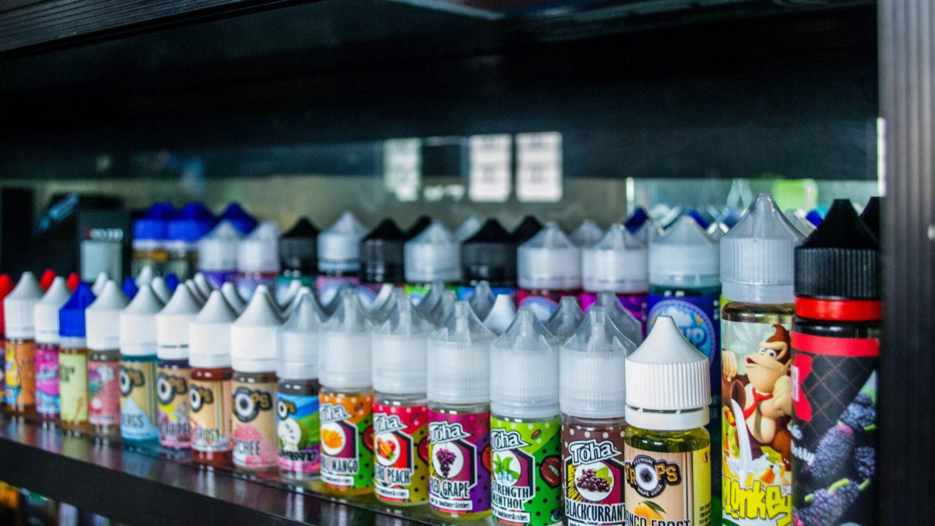 Rows of colorful e-liquid bottles displayed on shelves in a vape shop.