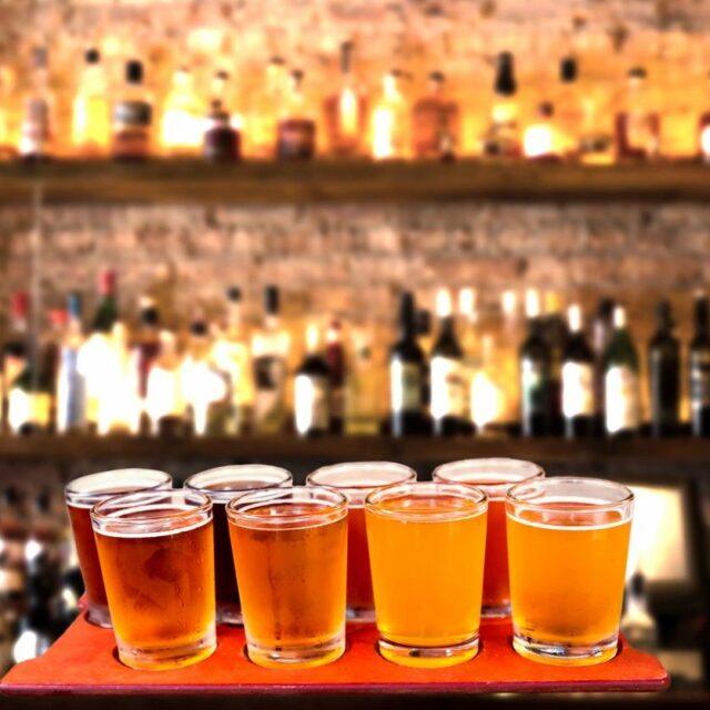 A row of beer glasses filled with amber ale on a bar counter.