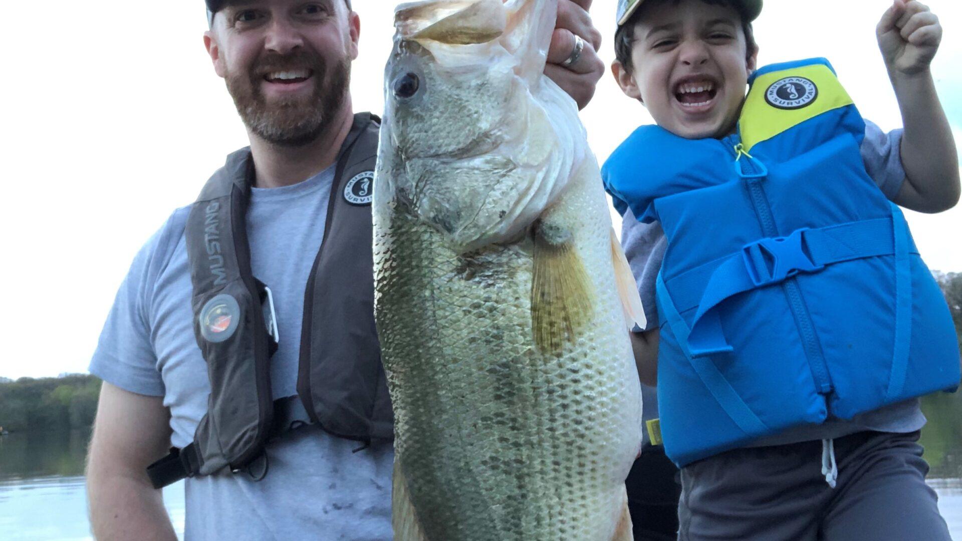 Man and child proudly hold a large fish they caught.