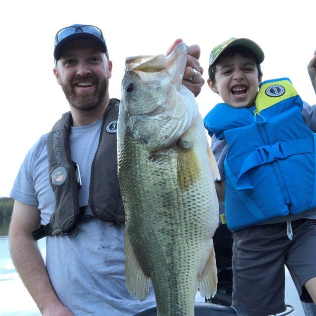 Man and child proudly hold a large fish they caught.