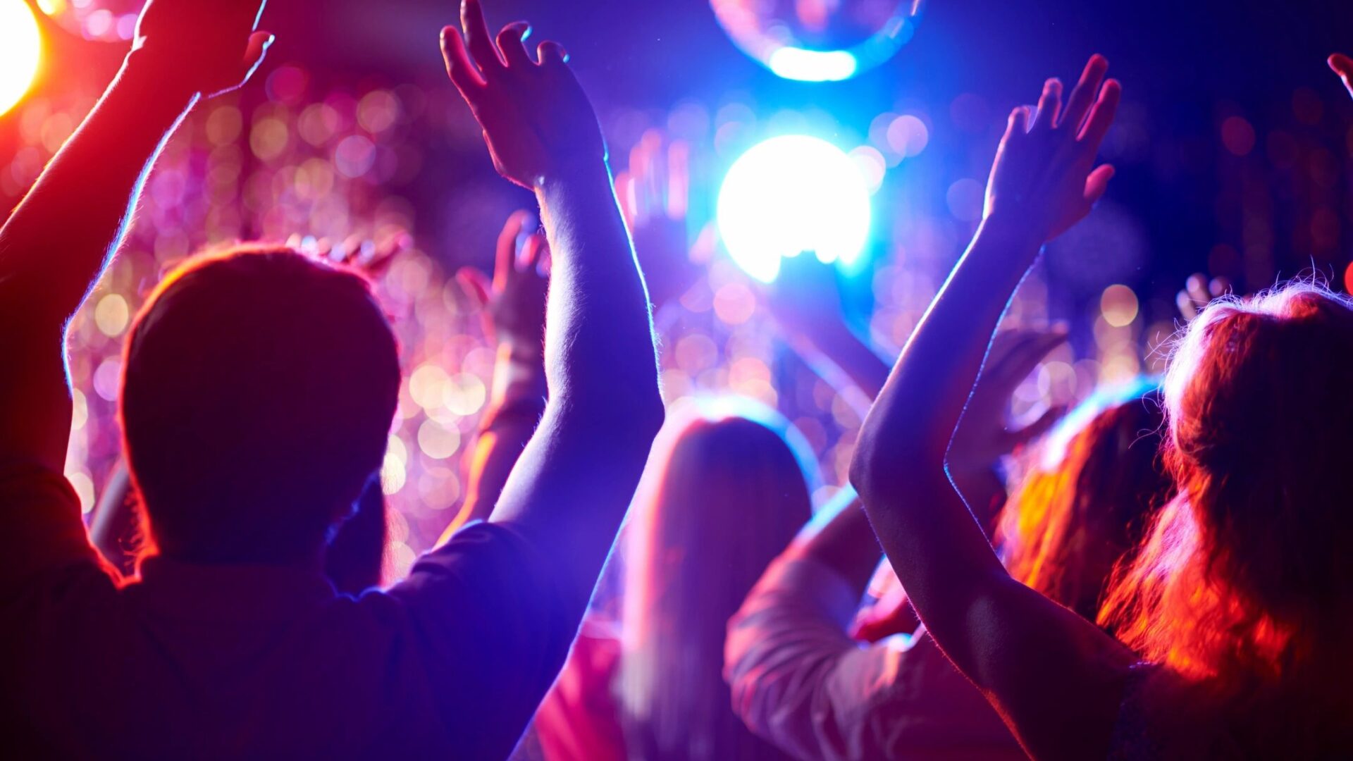 People dancing and enjoying a vibrant party with colorful lights.