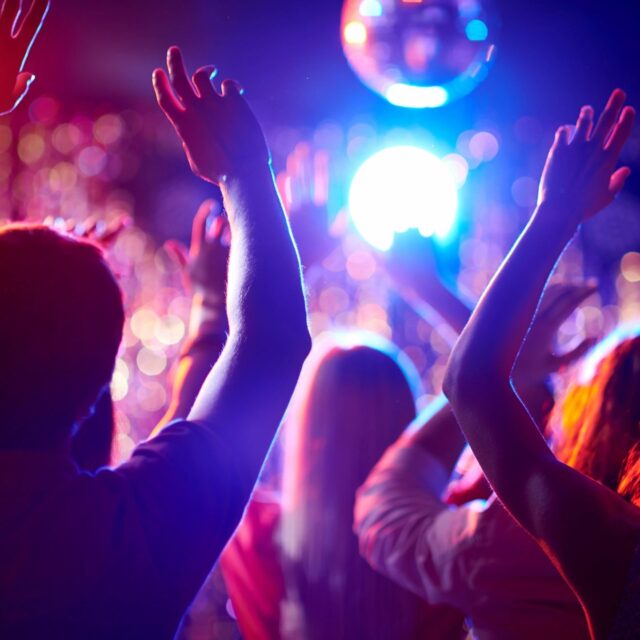 People dancing and enjoying a vibrant party with colorful lights.